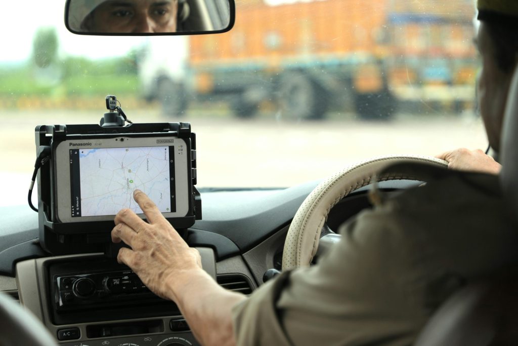 Police officer navigates using a digital map on a tablet inside a vehicle.