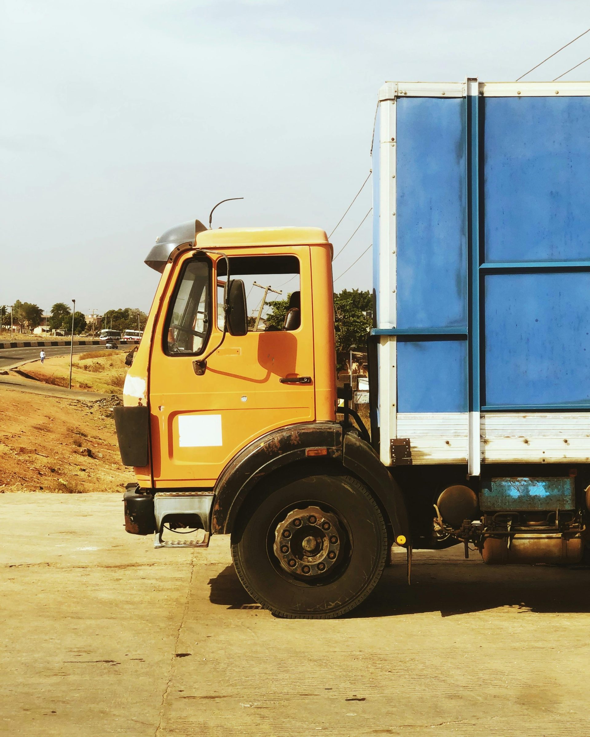 A colorful truck stands parked on a road in Nigeria, showcasing vibrant orange and blue colors.