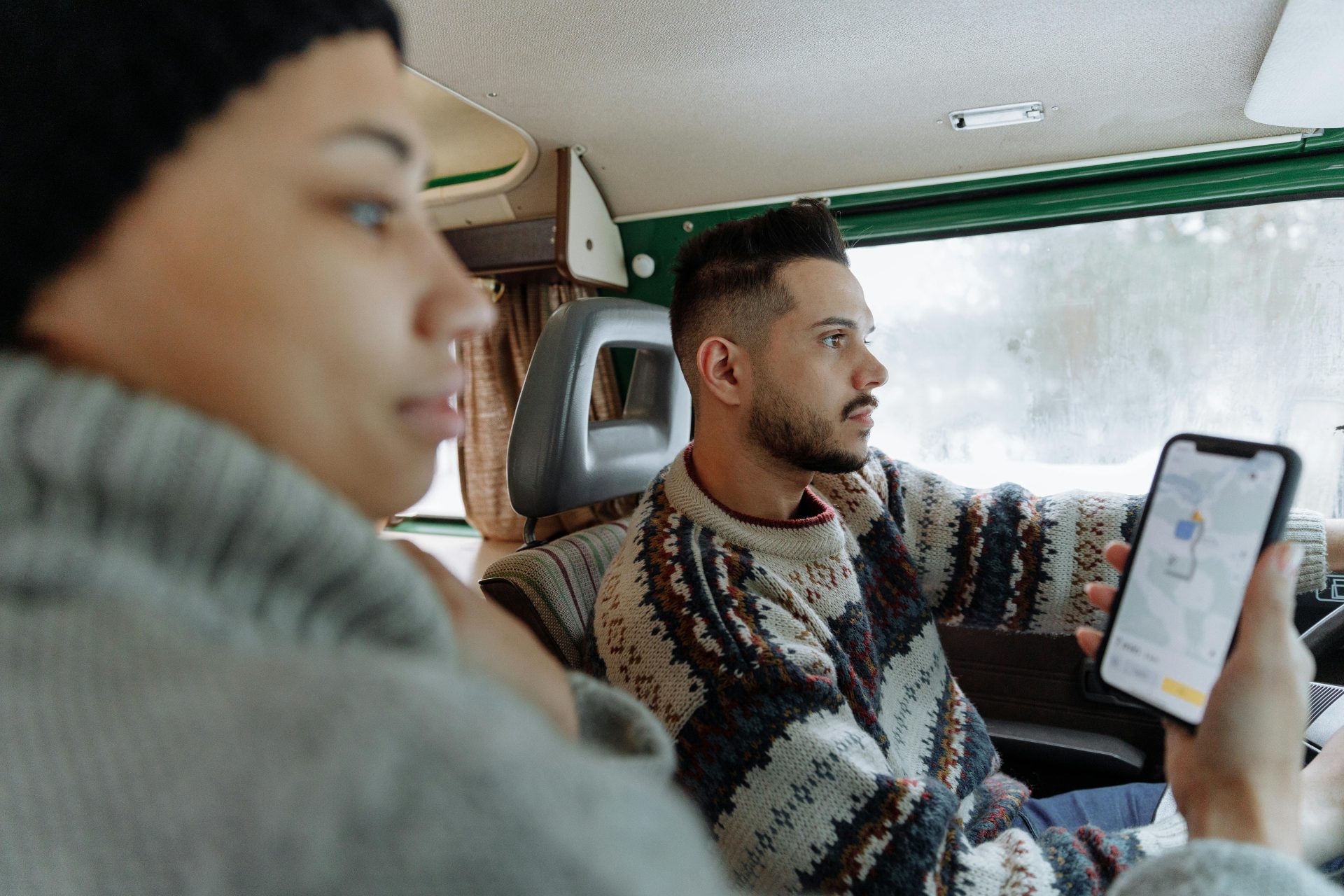 Couple using navigation app in a vintage campervan during a road trip.