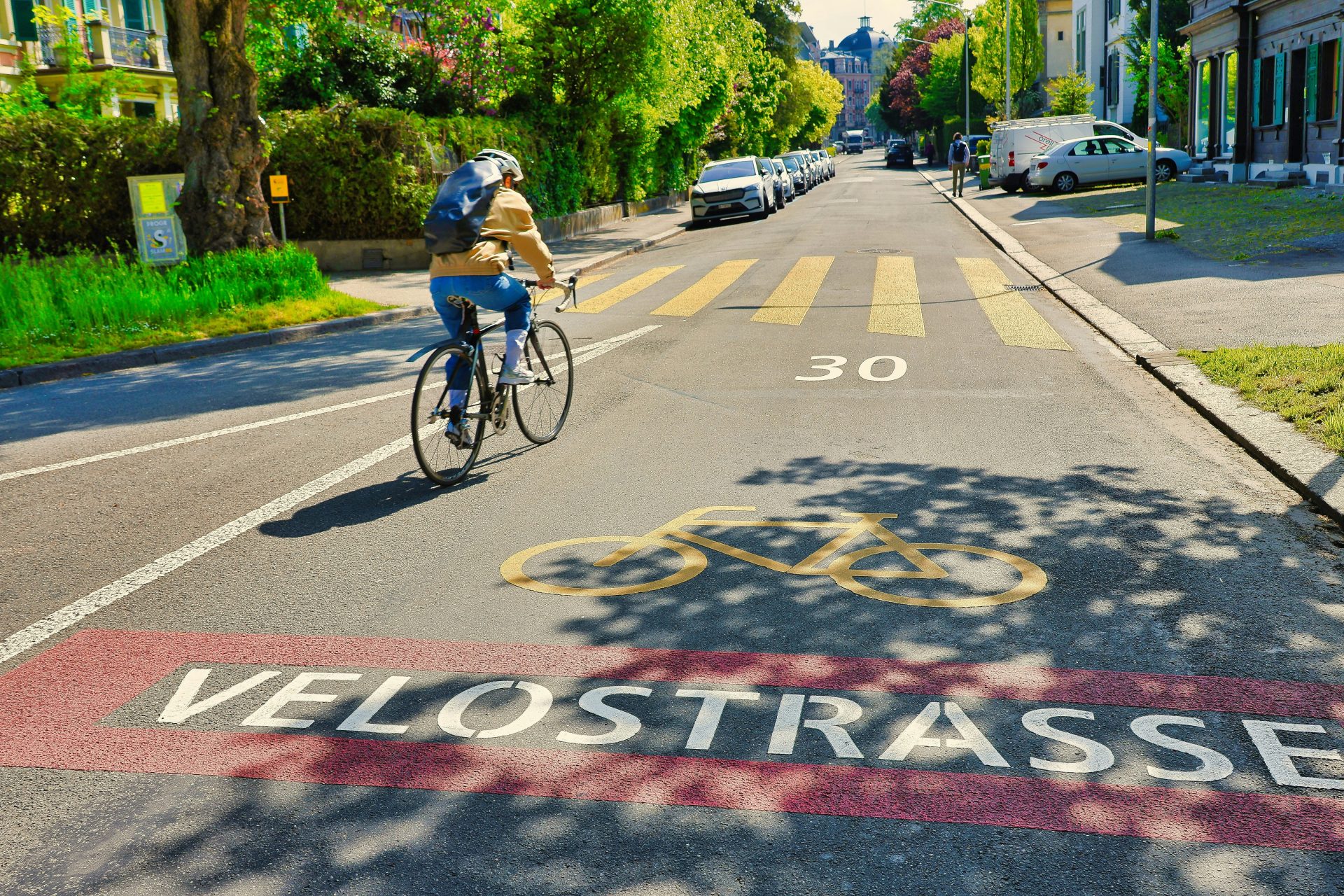 Cyclist rides on a marked "velostrasse" bike lane.